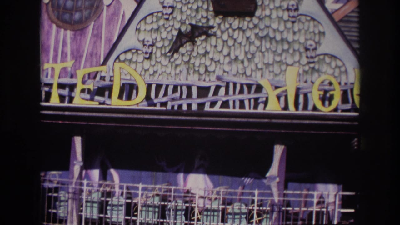 Similar view of the haunted facade with skull trim, bat cutout, yellow letters, and a dark balcony-like entrance.