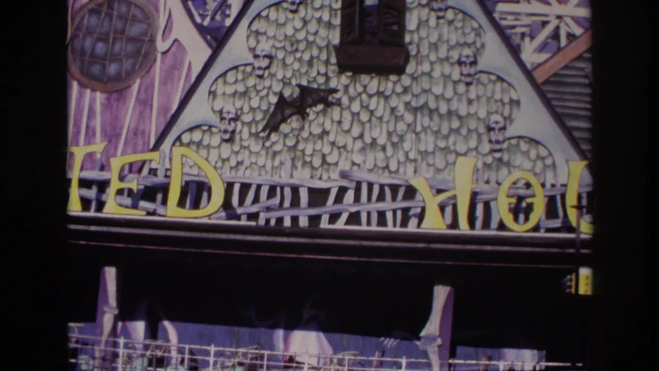 1967 8mm view of the Rockaway Beach haunted attraction facade, emphasizing the bat silhouette, skull ornamentation, yellow lettering, and shadowed lower entrance.