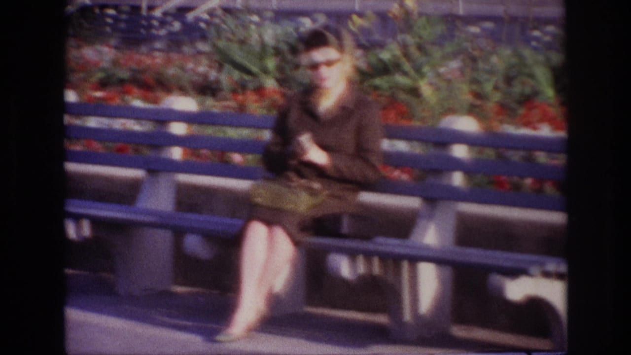 Seated woman adjusts her gloves on a blue bench outdoors.