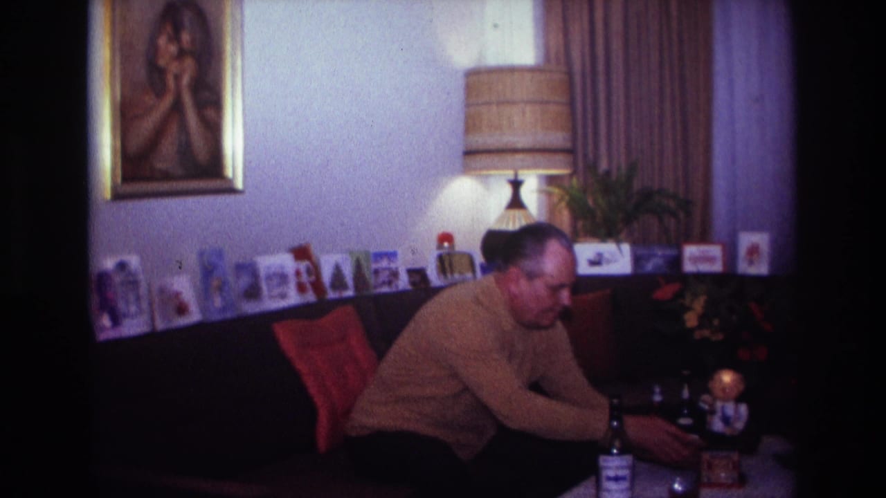 Man leans forward from a couch toward objects on a low table.