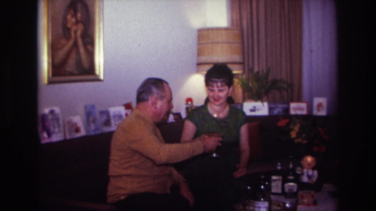 The man raises a small glass toward the woman during a home celebration in the Rockaway Beach, New York footage dated 1967.
