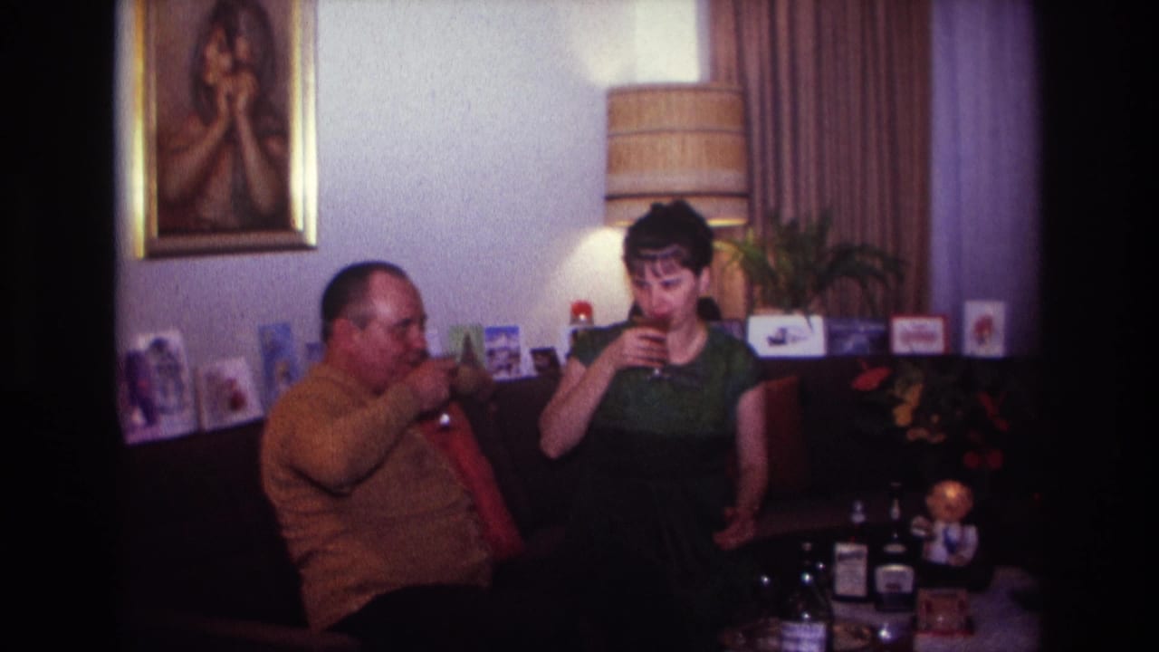 Couple on a couch sip drinks beside a table with bottles.