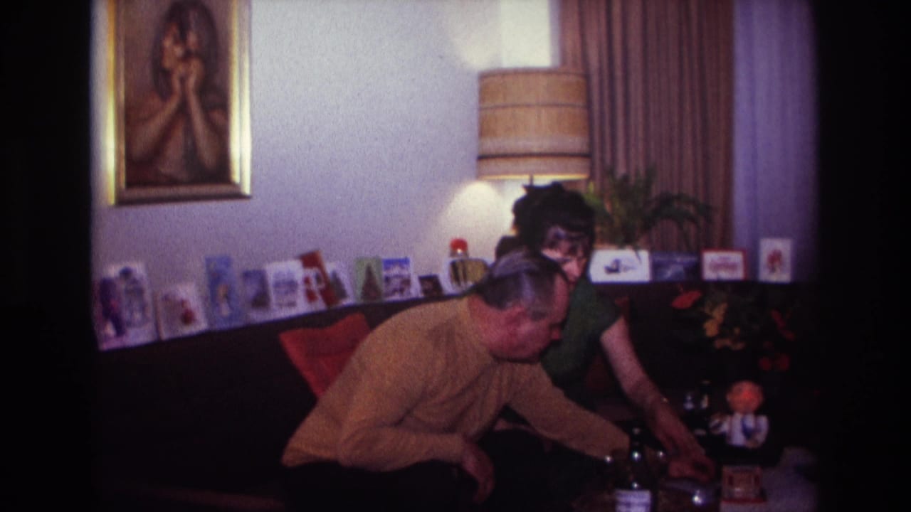 Couple seated close together as the man reaches toward items on a table.