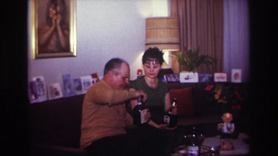At the end of the short 1967 living-room clip, the couple is still seated with bottles and a glass visible.