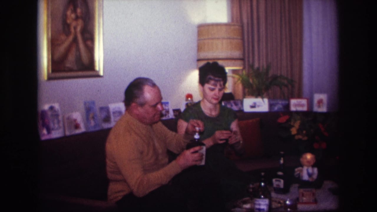 Man pours or handles a dark bottle while a woman looks down at something in her hands.