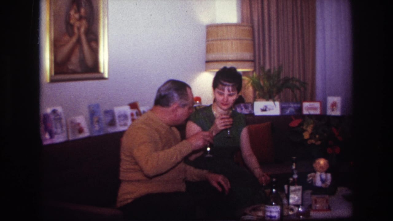 Man turns toward a woman as both hold wine glasses on a living room couch.