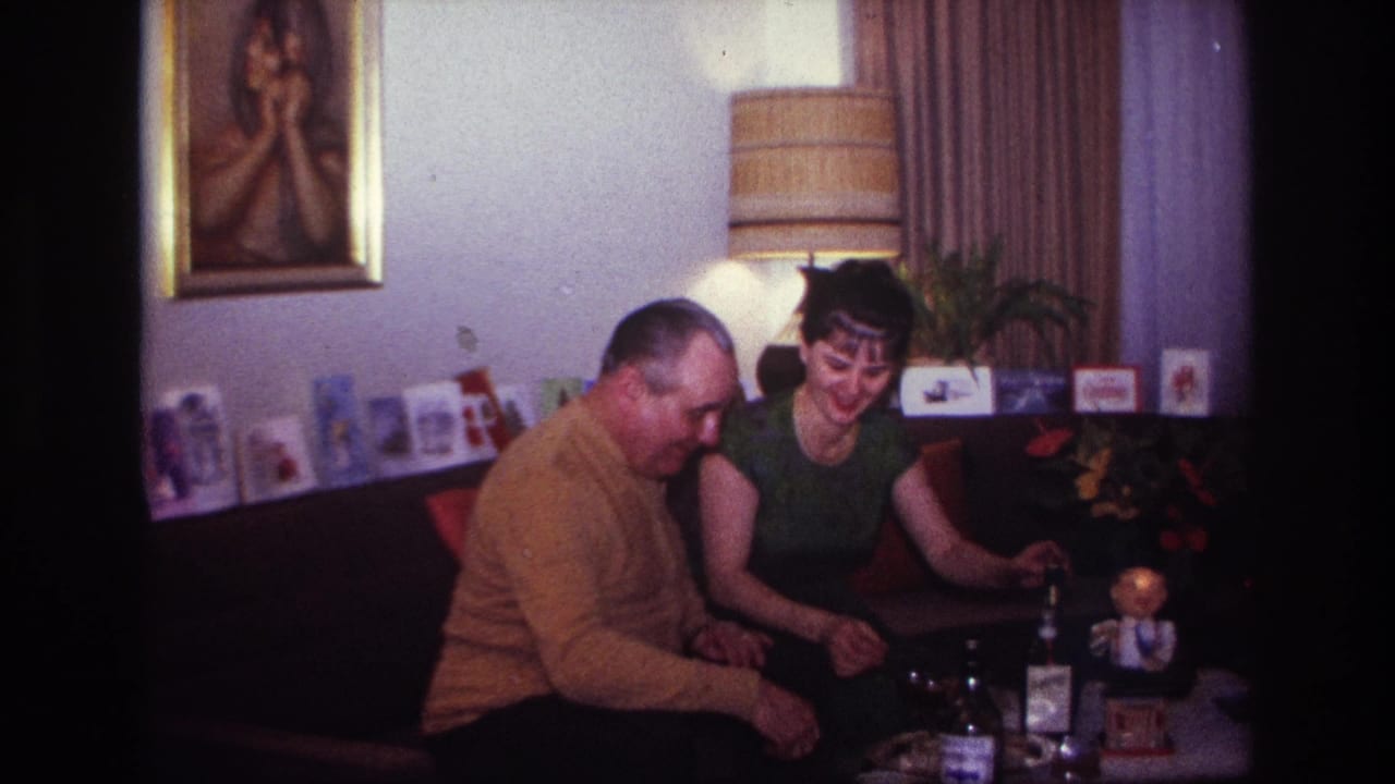 1967 Rockaway Beach living-room scene with two adults sharing drinks near a lamp, cards and framed wall art.