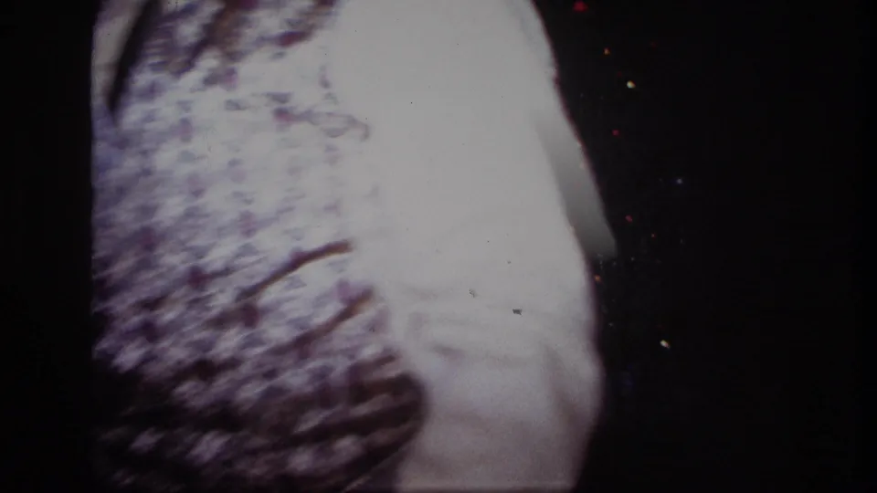 Blurred 8mm close-up from the Rockaway Beach Christmas interior, dominated by patterned vest fabric and a bright sleeve.