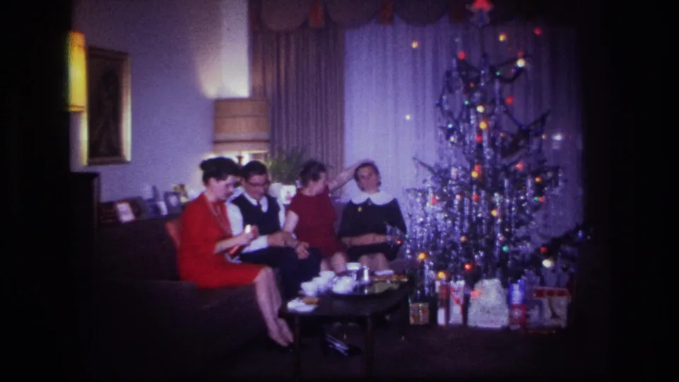 Four adults in dress clothing sit near a tinsel Christmas tree during a 1967 Rockaway Beach family gathering.
