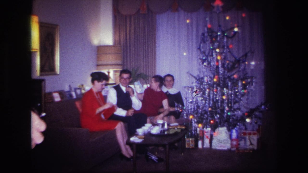 In a 1967 Rockaway Beach home movie, four adults sit by a silver tinsel Christmas tree with cups and presents nearby.