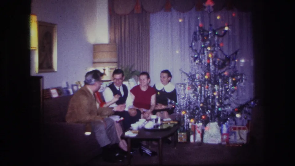 Rockaway Beach 1967 home-movie still of a family group reacting together on a sofa near a decorated Christmas tree.