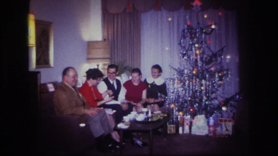 Rockaway Beach 1967 home-movie still showing five people seated beside a silver Christmas tree in a private living room.