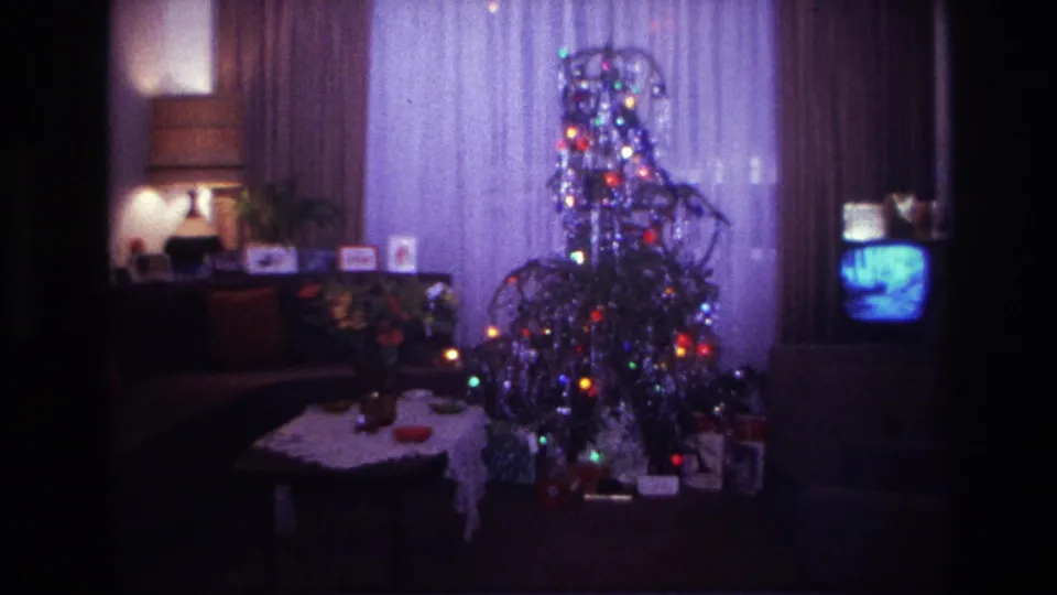 1967 Rockaway Beach living-room frame with an aluminum Christmas tree, wrapped gifts, coffee table, lamp, curtains, and small television.