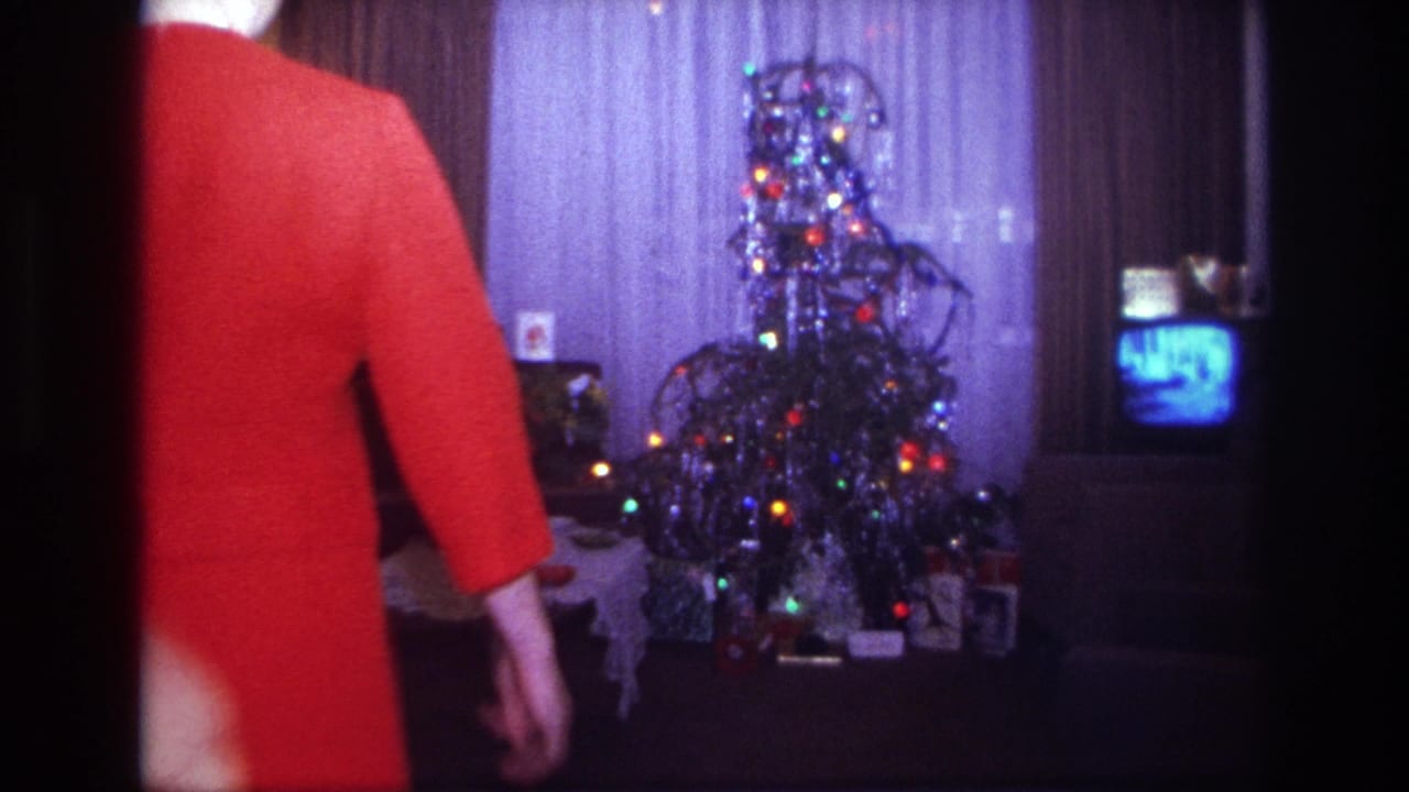 1967 Rockaway Beach home-movie frame of adults entering a living room toward a decorated Christmas tree and small television.