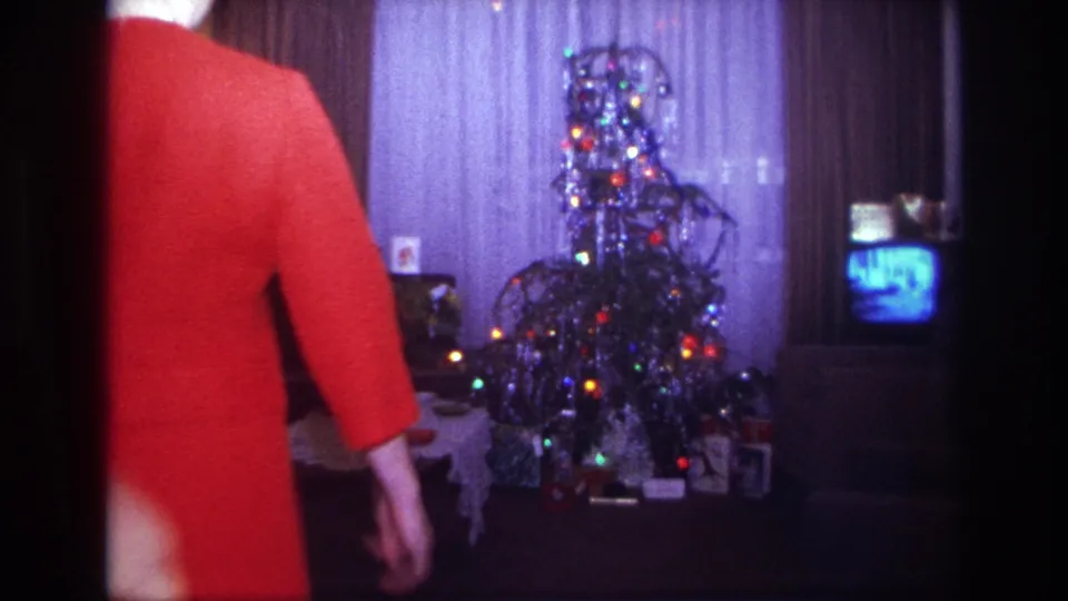 1967 Rockaway Beach home-movie frame of adults entering a living room toward a decorated Christmas tree and small television.