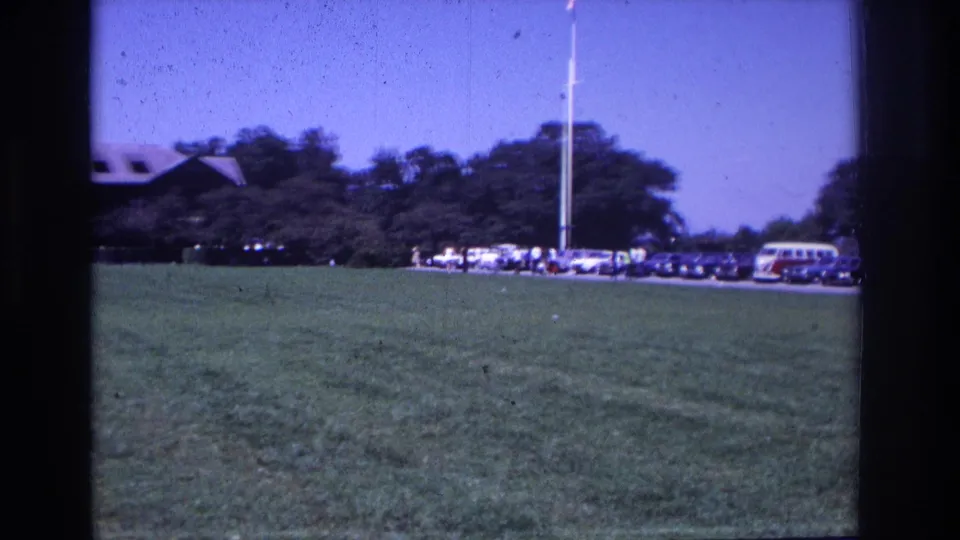 1968 Ocean City, New Jersey home-movie frame showing a grassy parking area with classic cars, a VW bus, trees, and a flagpole.