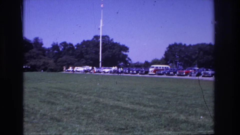 Ocean City, New Jersey 1968 frame with a lawn foreground, parked 1960s cars, small pedestrians, trees, and a flagpole.