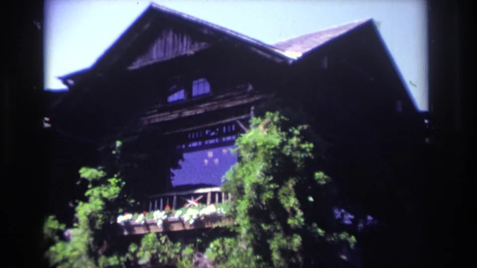 Handheld 8mm view of the upper stories of a large ivy-covered Ocean City house with balcony and surrounding trees.