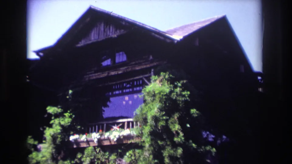 1968 Ocean City home-movie frame showing a large dark timber building partly obscured by leafy trees.