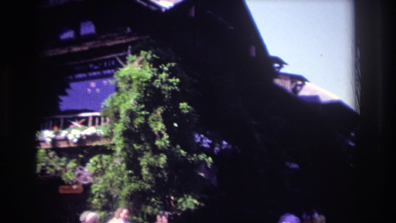 1968 Ocean City frame with a timber building, balcony, green tree, and distant visitors near the lower edge.