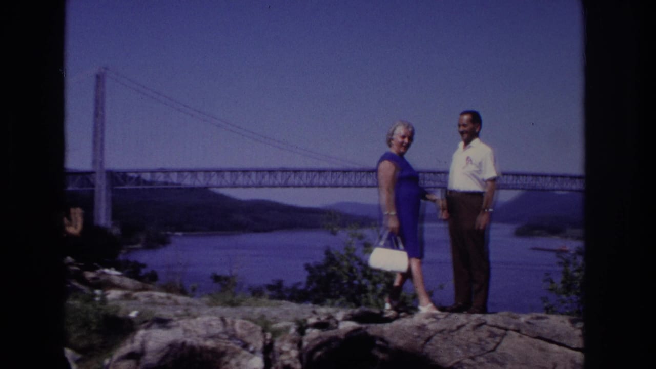 Couple posed near a bridge overlook, separated by a dark film-frame divider.