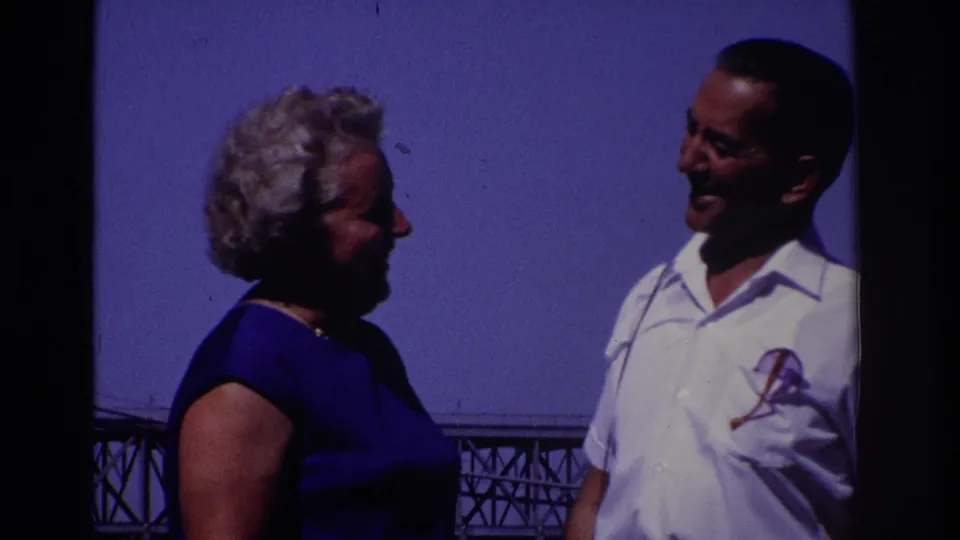 1968 Ocean City, New Jersey home-movie frame of a smiling adult couple standing close together with a bridge behind them.