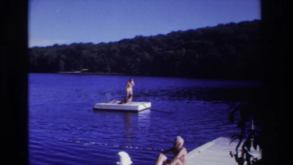 1968 Ocean City, New Jersey 8mm frame showing a person on a floating lake dock while an older man sits near the foreground pier.