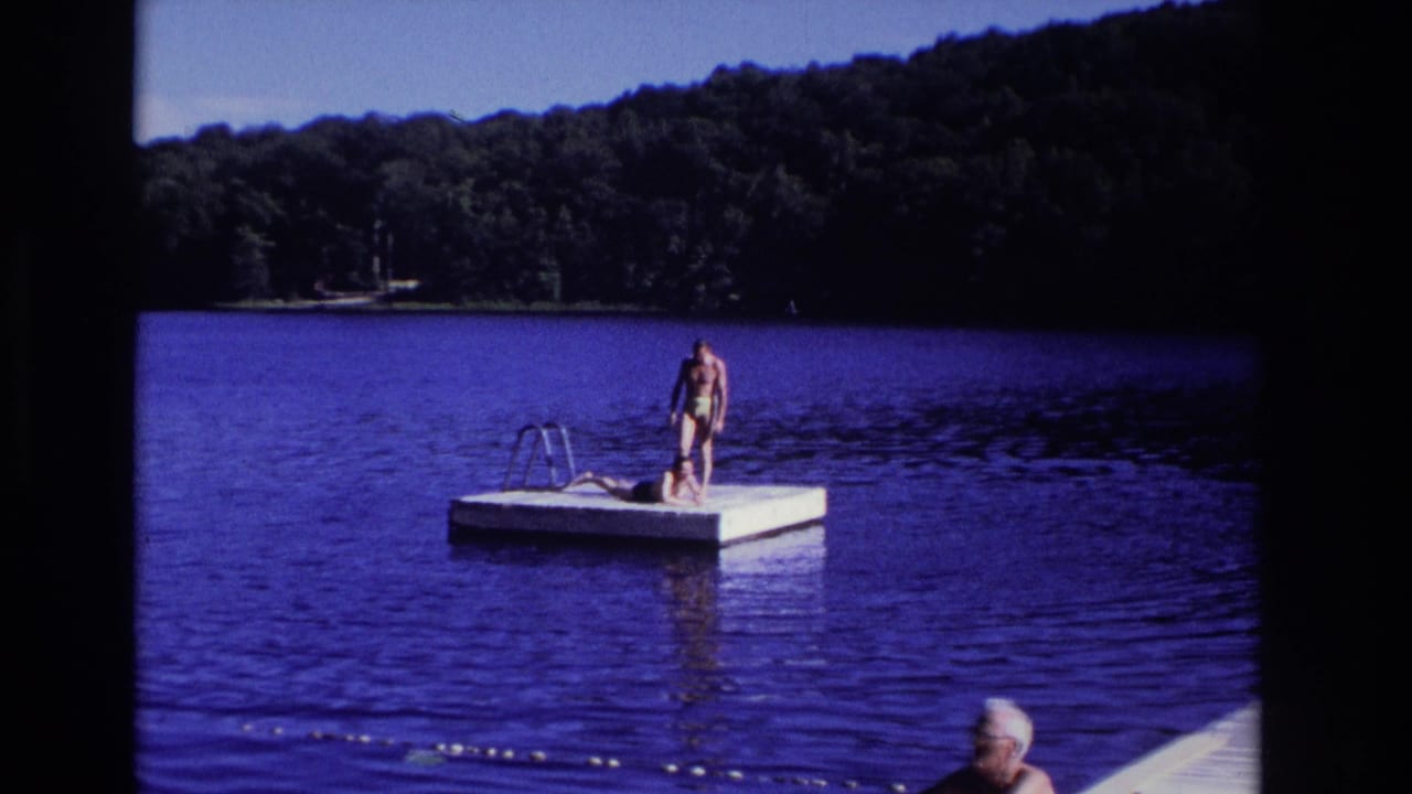 1968 Ocean City, New Jersey home-movie frame of two people on a white floating dock in a calm blue lake.