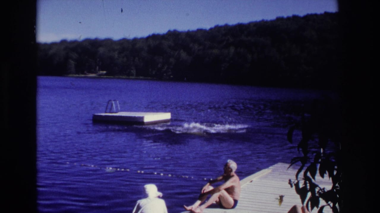 1968 Ocean City, New Jersey home-movie frame showing dockside swimmers, blue lake water, and a floating swim platform near a wooded shore.