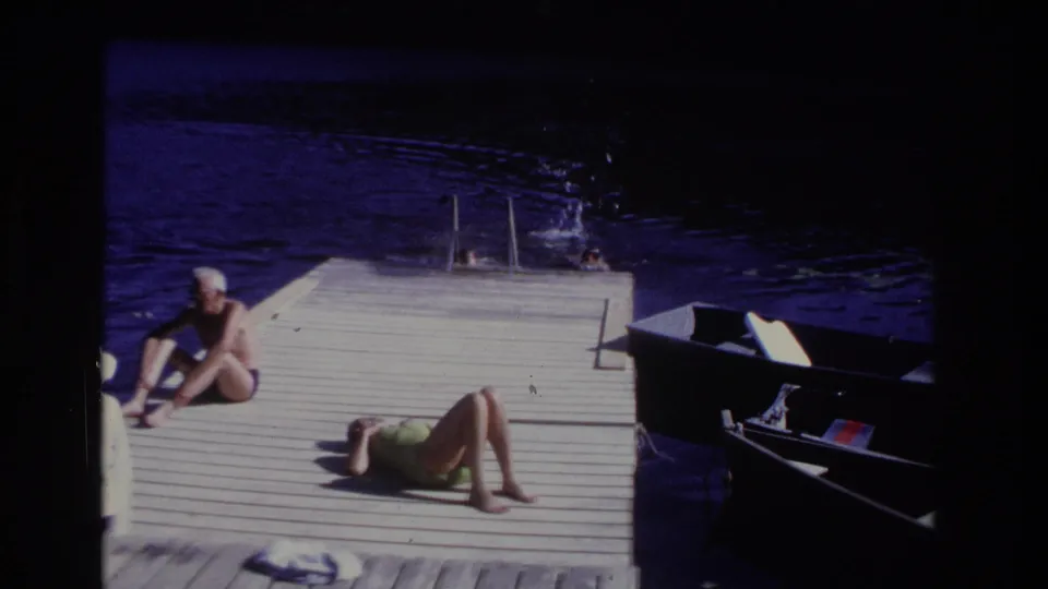 Ocean City 1968 home-movie frame showing swimmers near a ladder with adults relaxing on the dock beside a boat.