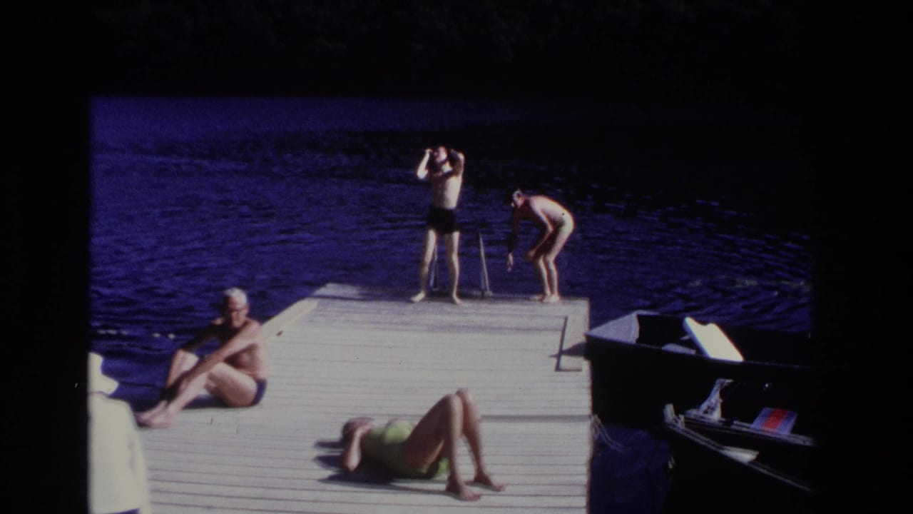 Two adults stand at the end of a dock while others sit and recline nearby.