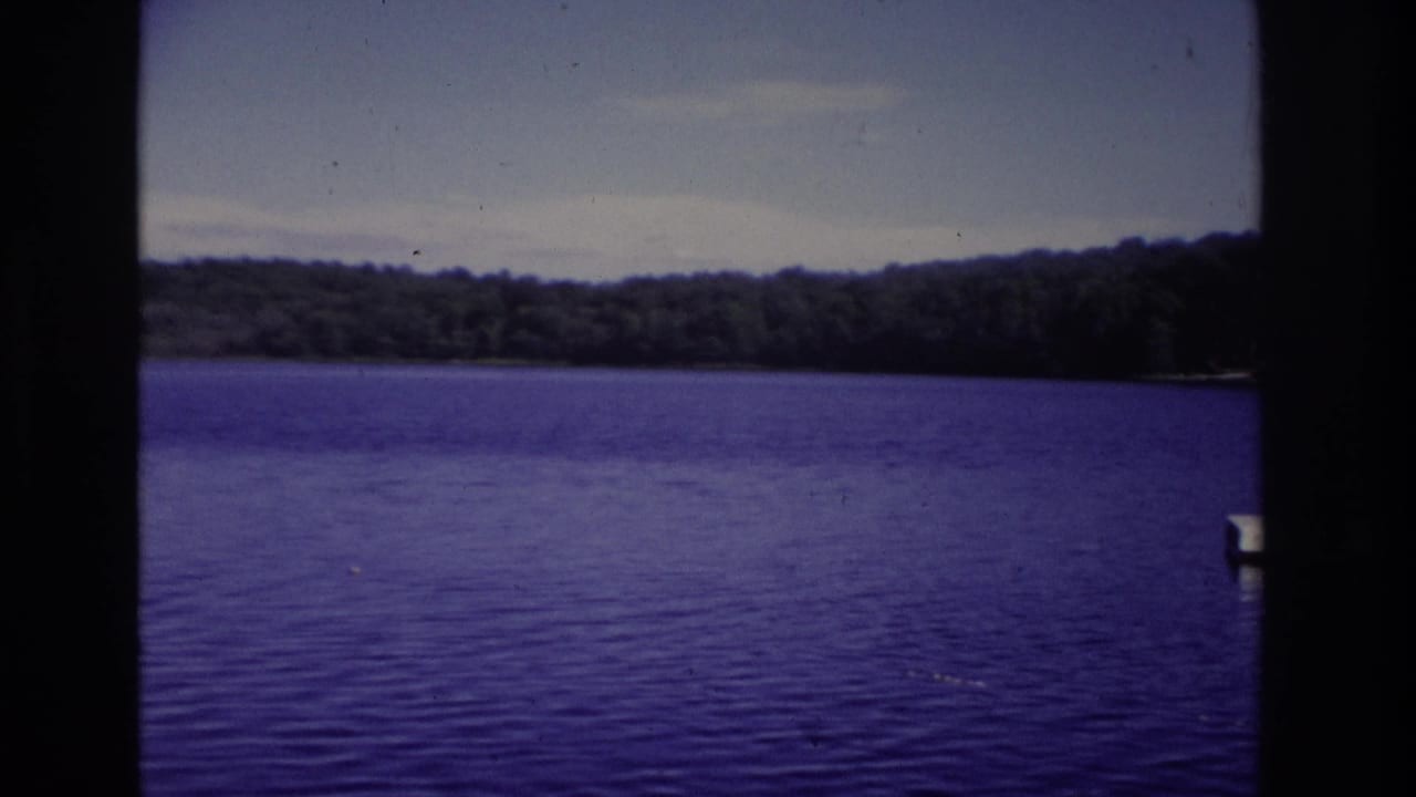 1968 Ocean City home-movie frame showing a calm lake, distant treeline, open sky, and dark film-strip borders.