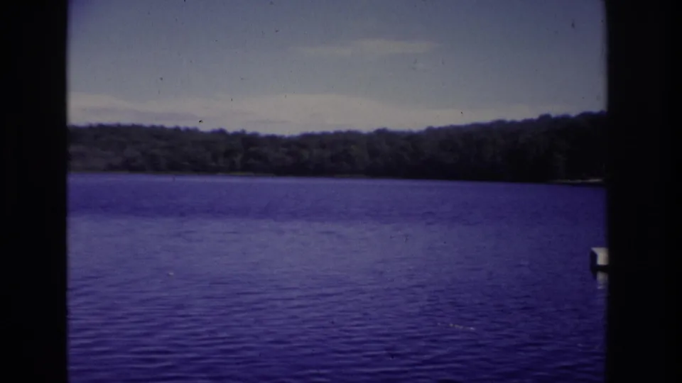 1968 Ocean City home-movie frame showing a calm lake, distant treeline, open sky, and dark film-strip borders.