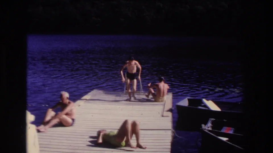 1968 Ocean City dock scene with adults in swimwear relaxing near the water and a small boat alongside.