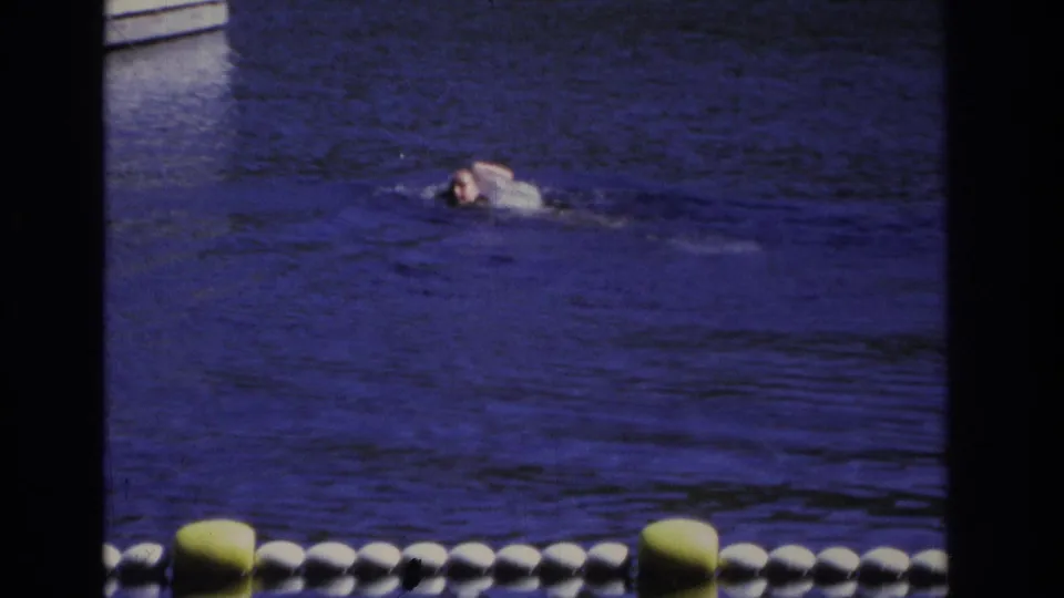 1968 Ocean City frame showing a distant person swimming across calm water, with a buoy line low in the foreground.