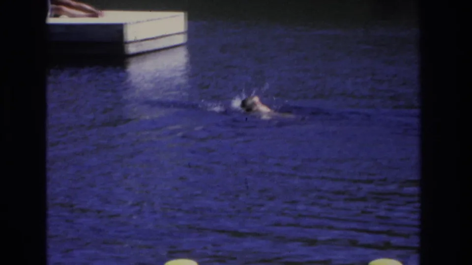 Distant swimmer in Ocean City, New Jersey, visible in blue water near a dock edge in 1968 8mm home-movie footage.