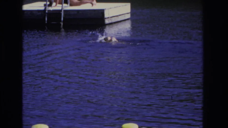 1968 8mm frame from Ocean City showing the monkey splashing near the dock ladder in strongly tinted blue water.