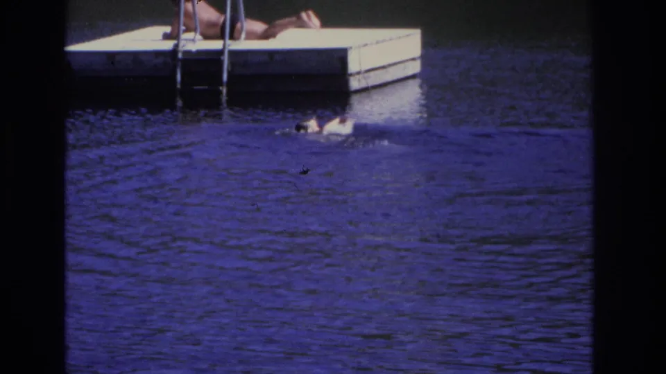 Ocean City 1968 home-movie frame showing the monkey close to the dock below a partially visible person on the platform.