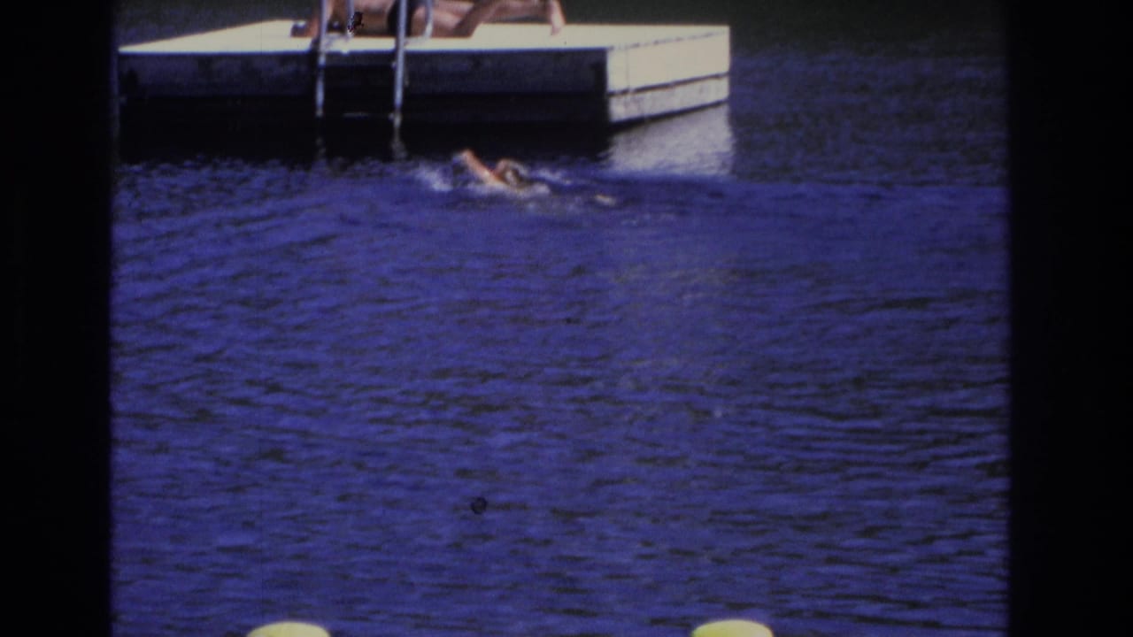 1968 Ocean City home-movie frame showing a swimmer in rippled blue water near a floating dock and ladder.