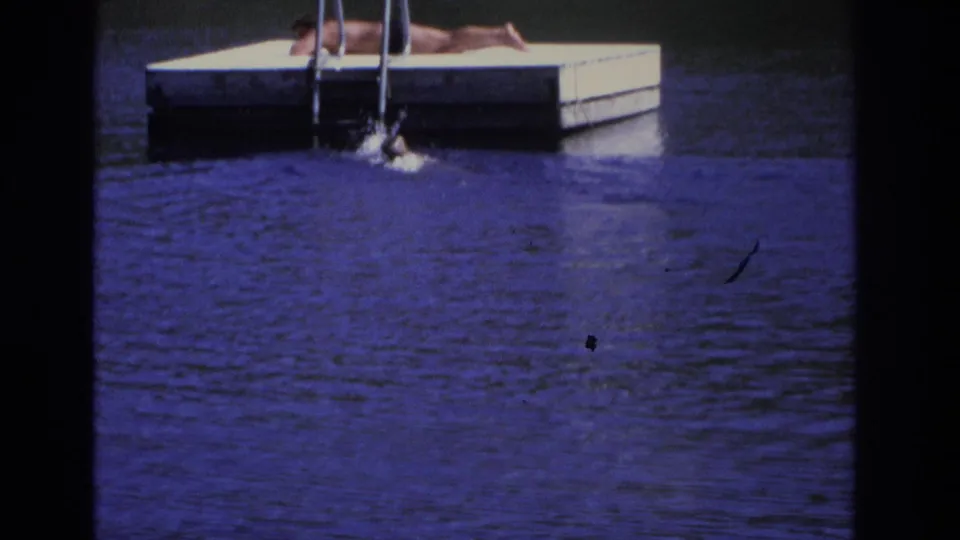 1968 Ocean City home-movie frame showing a swimmer splashing at the ladder on a small dock.