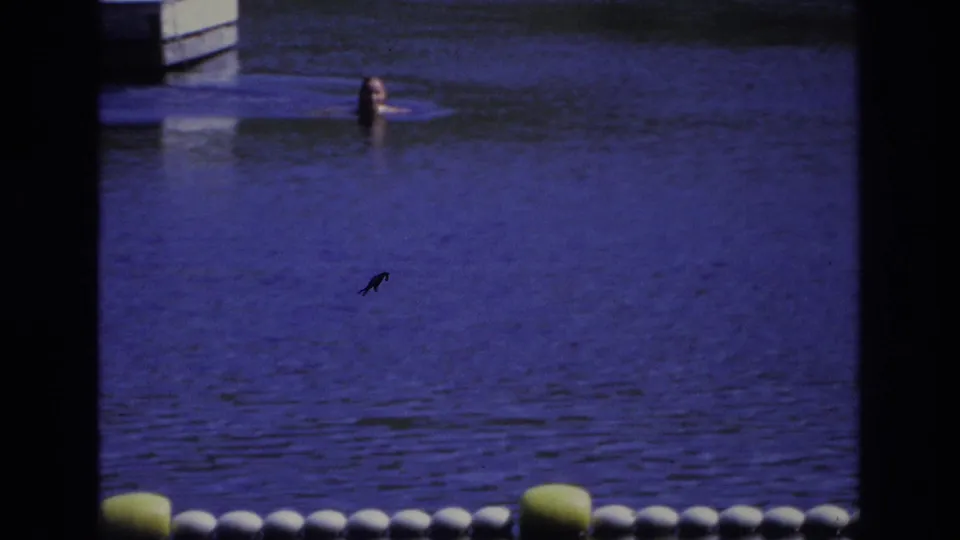 1968 Ocean City frame with a distant person in the water beyond a buoy line, partly obscured by dark foreground framing.