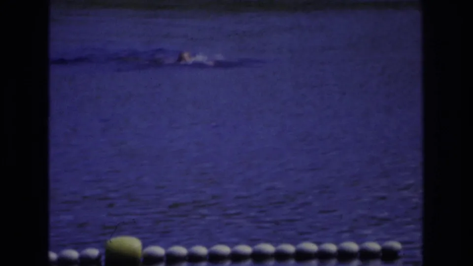 1968 Ocean City home-movie frame showing a distant swimmer in blue-tinted water behind a white float line and yellow buoy.