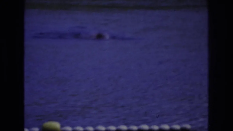 1968 Ocean City frame with a swimmer partly visible in blue water, a float line, and a yellow buoy near the foreground.