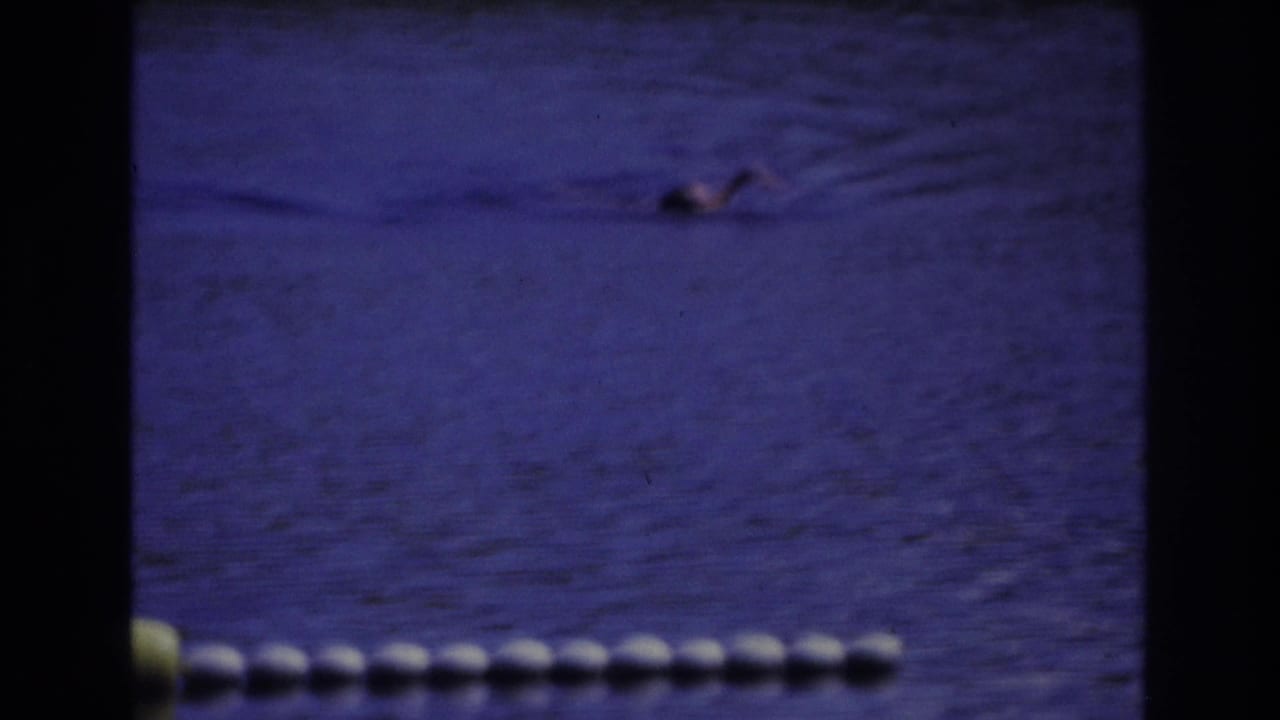 Distant swimmer in blue-tinted water with a buoy line across the lower frame.