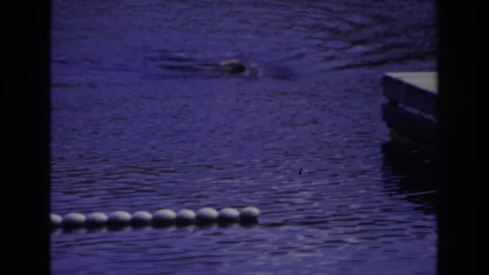 1968 Ocean City 8mm frame with a swimmer, foreground buoys, dark borders, and a dock edge entering from the right.