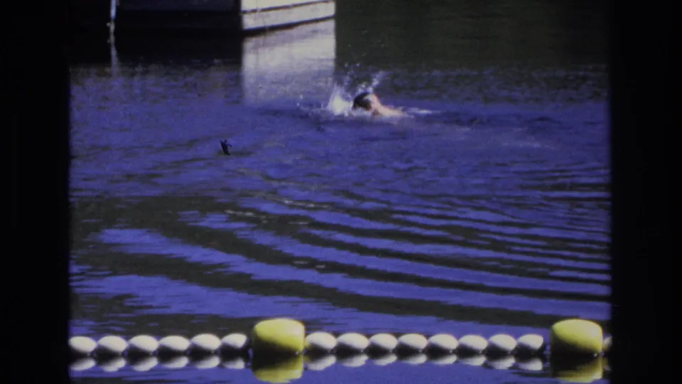 1968 Ocean City 8mm frame showing a swimmer moving through rippled blue water near a buoy line and dock structure.