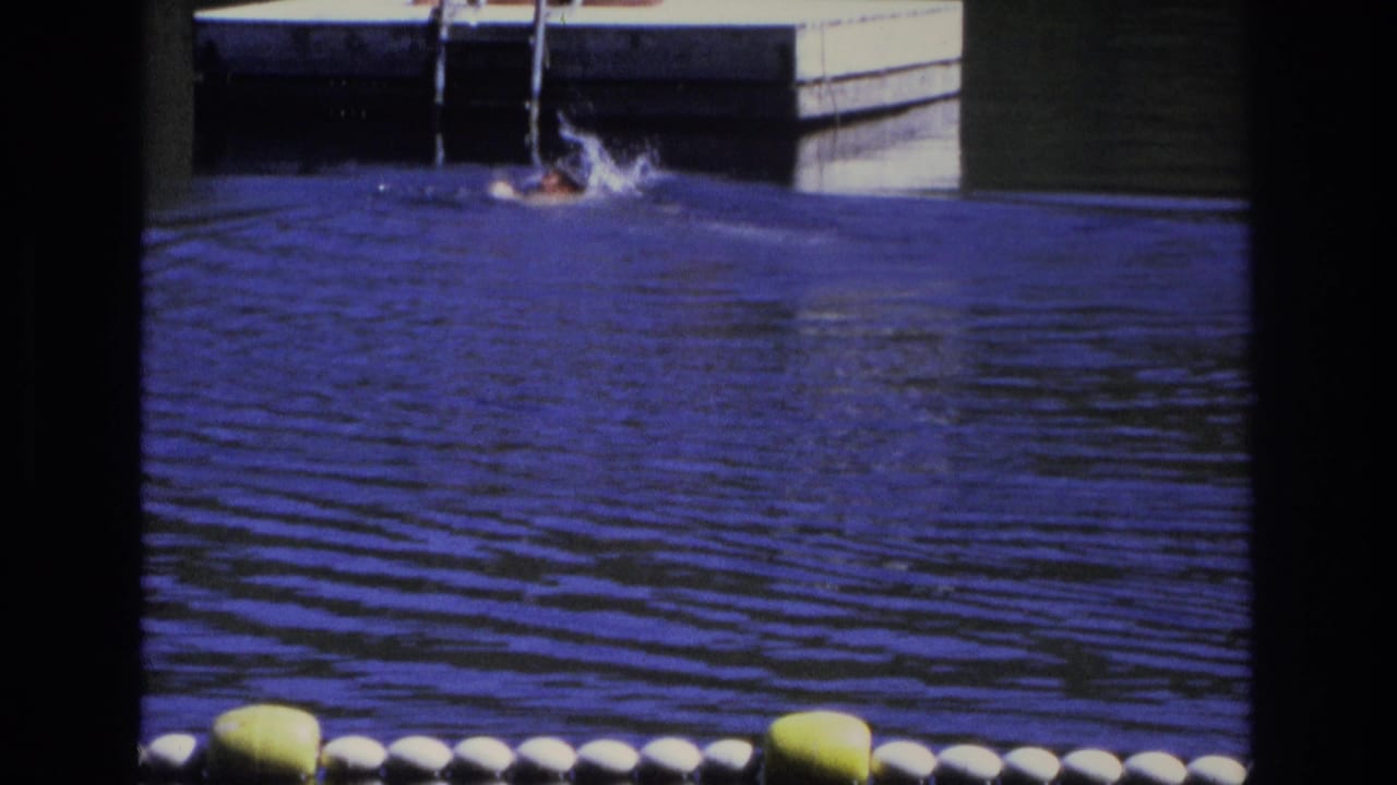 Splashing swimmer near a floating dock ladder on blue water.
