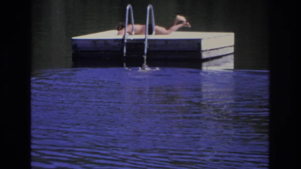 Ocean City 1968 frame with a person stretched on a floating dock above rippled blue water and a metal ladder.