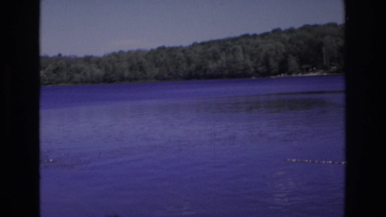 Wide lake view with wooded hills and a buoy line near the right edge.