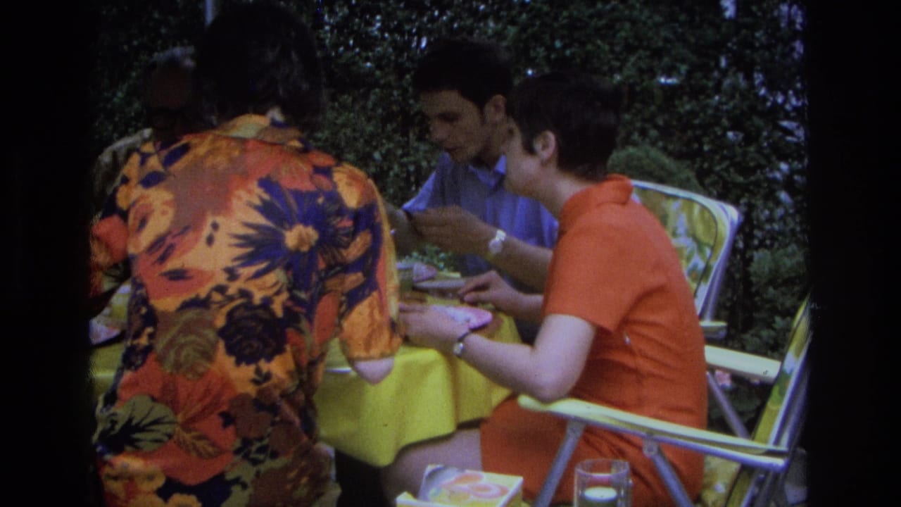Adults continue eating at an outdoor table beside garden greenery.